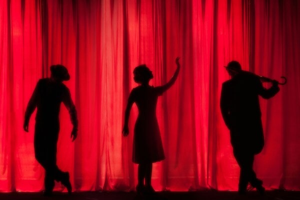 silhouette de trois artistes sur scène