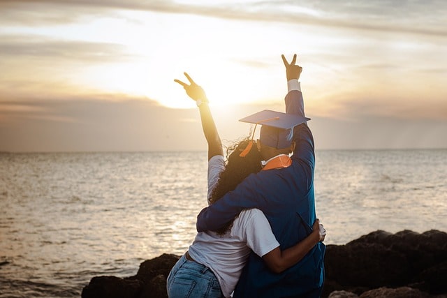 A student celebrating his graduation by the sea